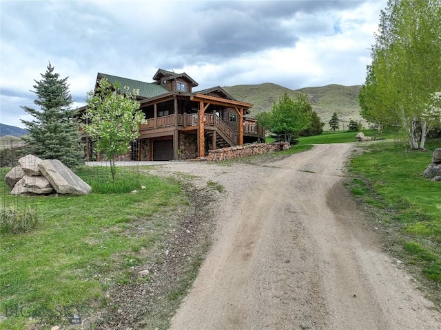 view of front of property featuring a garage, a front yard, and a deck with mountain view