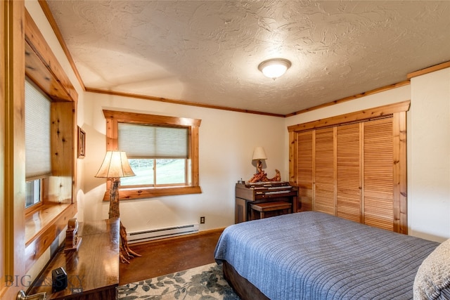 bedroom with a closet, a textured ceiling, a baseboard heating unit, and crown molding