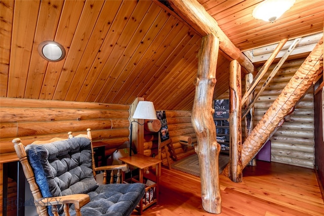 living area with hardwood / wood-style flooring, wooden ceiling, and rustic walls