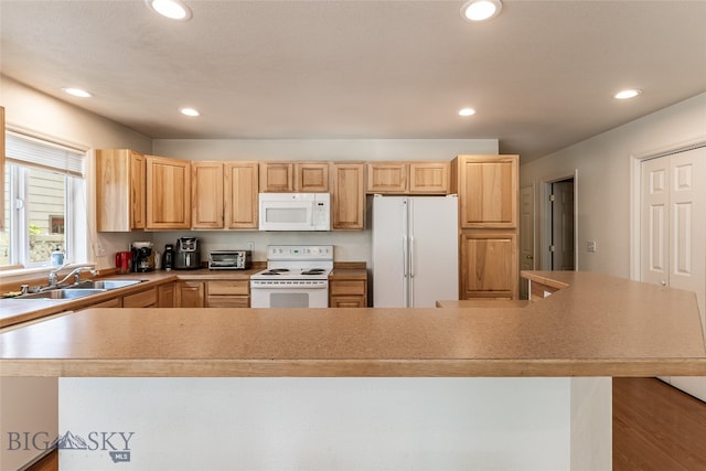 kitchen featuring white appliances, sink, a kitchen island, light brown cabinetry, and hardwood / wood-style flooring