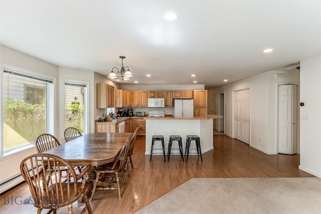 dining area featuring light hardwood / wood-style flooring, a notable chandelier, a wealth of natural light, and baseboard heating