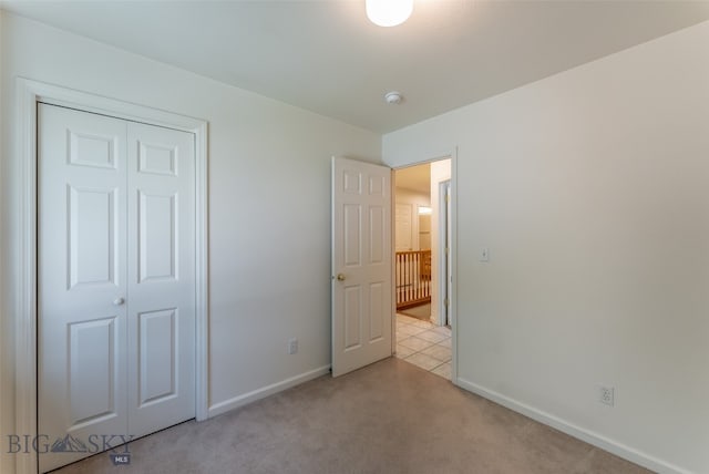 unfurnished bedroom with light carpet and a closet