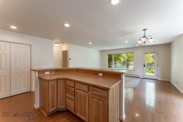 kitchen with light hardwood / wood-style flooring, decorative light fixtures, a kitchen island, a baseboard radiator, and a notable chandelier