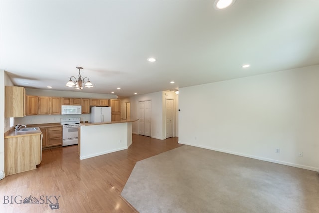 kitchen featuring a notable chandelier, light wood-type flooring, white appliances, sink, and a center island