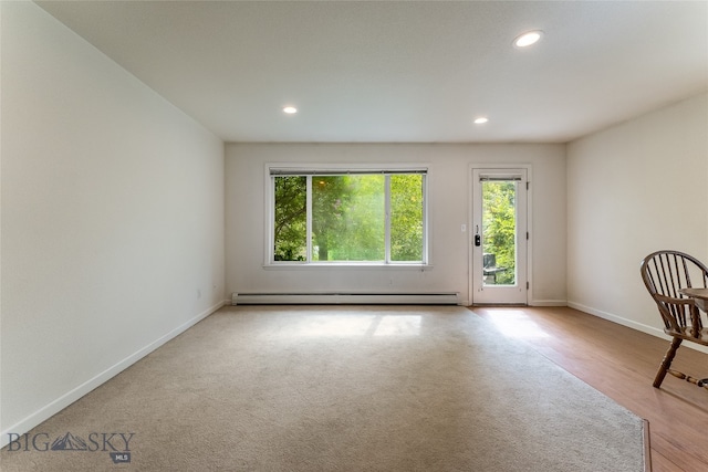 spare room with hardwood / wood-style flooring and a baseboard heating unit