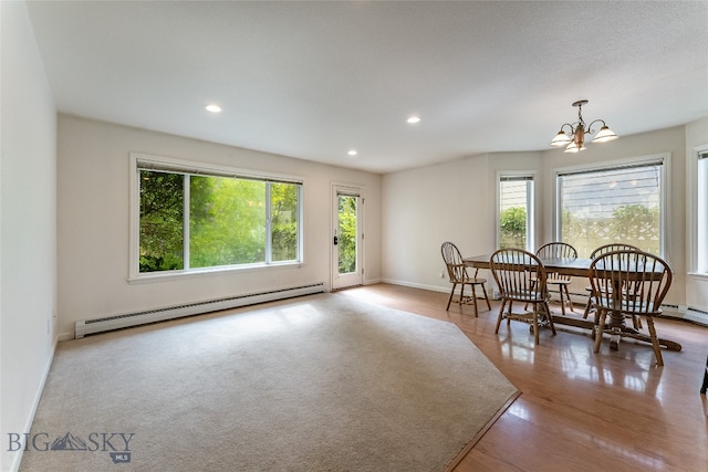 dining room featuring a baseboard radiator, wood-type flooring, a healthy amount of sunlight, and a chandelier