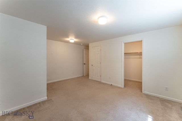 unfurnished bedroom with a walk in closet, a closet, and carpet flooring