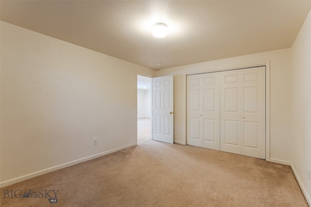 unfurnished bedroom with a closet and light colored carpet