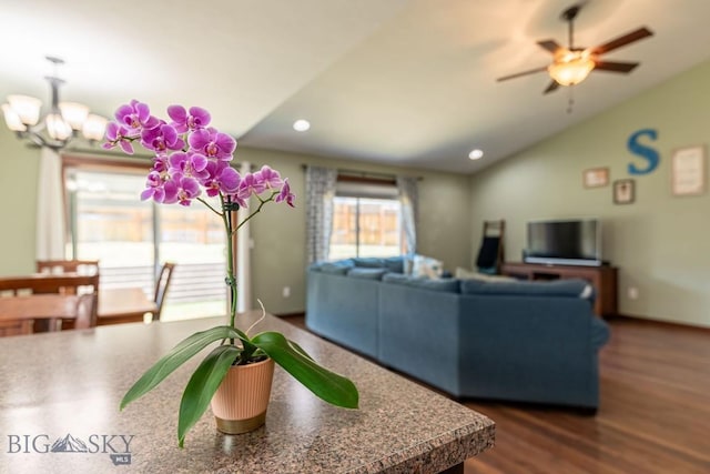 living room with ceiling fan with notable chandelier, hardwood / wood-style flooring, and lofted ceiling