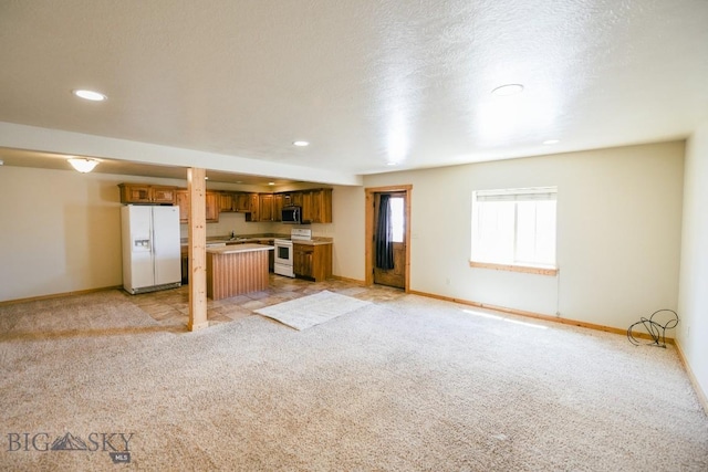 unfurnished living room featuring light carpet and a textured ceiling