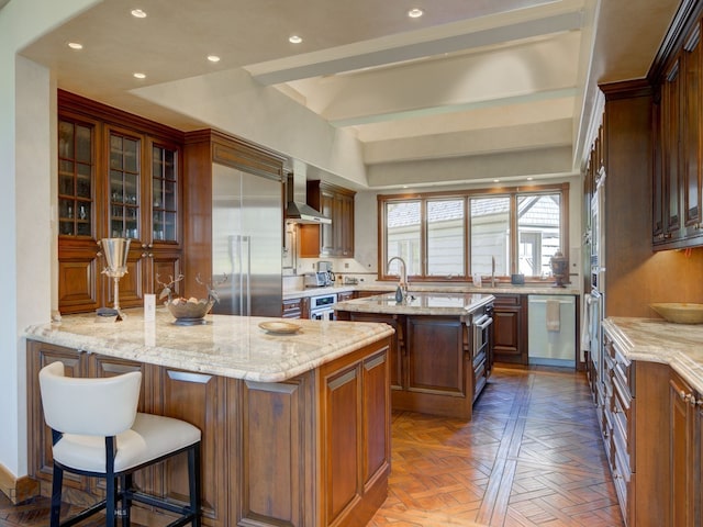 kitchen featuring parquet floors, stainless steel appliances, light stone countertops, a center island, and wall chimney exhaust hood