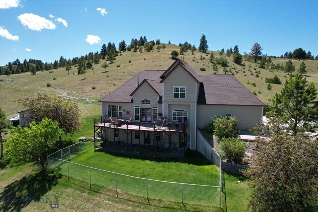 back of property featuring a deck, a lawn, and a rural view