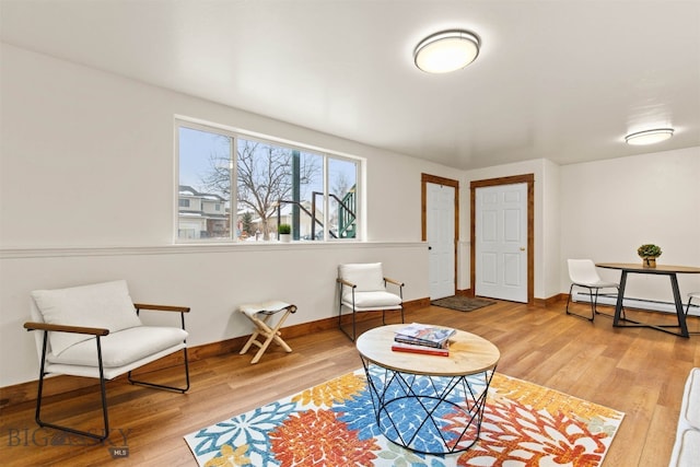 living area with a baseboard radiator and wood-type flooring