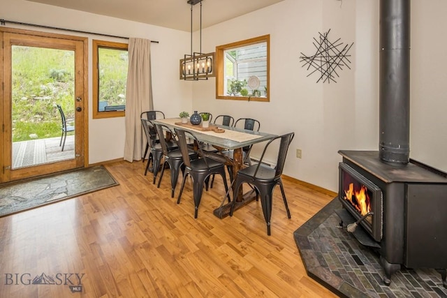 dining area with a wood stove, plenty of natural light, and light hardwood / wood-style flooring