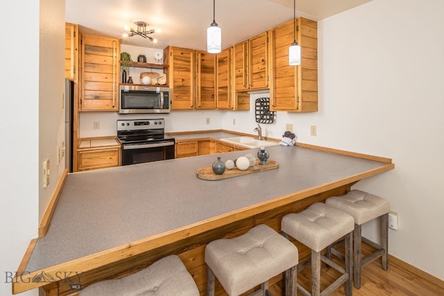 kitchen with a breakfast bar, kitchen peninsula, sink, and appliances with stainless steel finishes