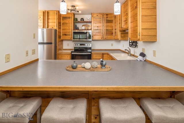 kitchen with decorative light fixtures, sink, kitchen peninsula, and stainless steel appliances