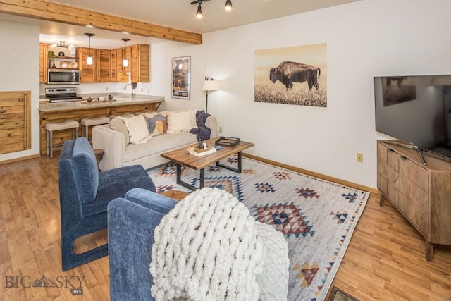 living room featuring beam ceiling, sink, and light hardwood / wood-style flooring