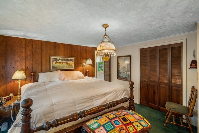 bedroom with wood walls, dark colored carpet, a closet, and a textured ceiling