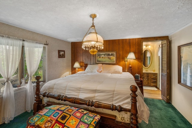 bedroom with wood walls, ensuite bathroom, radiator, a textured ceiling, and dark carpet