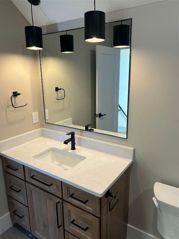 bathroom featuring vanity, lofted ceiling, and toilet