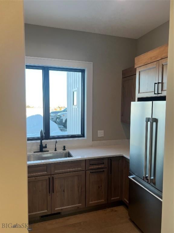 kitchen featuring sink, high end refrigerator, and dark hardwood / wood-style flooring