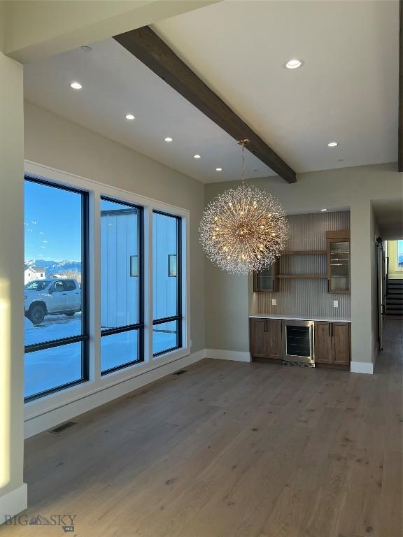 interior space featuring beamed ceiling, dark wood-type flooring, beverage cooler, and an inviting chandelier