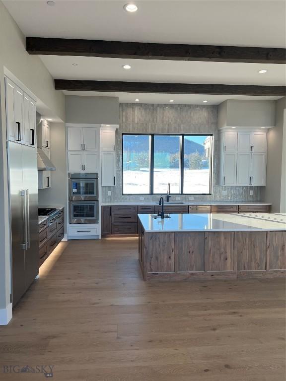 kitchen with appliances with stainless steel finishes, dark wood-type flooring, white cabinets, and backsplash