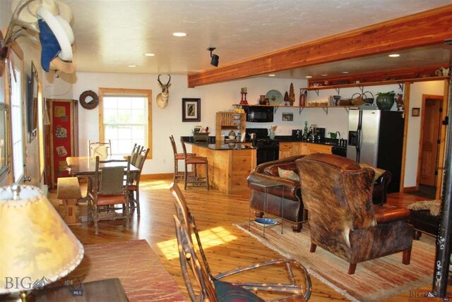 living room with beamed ceiling and light wood-type flooring