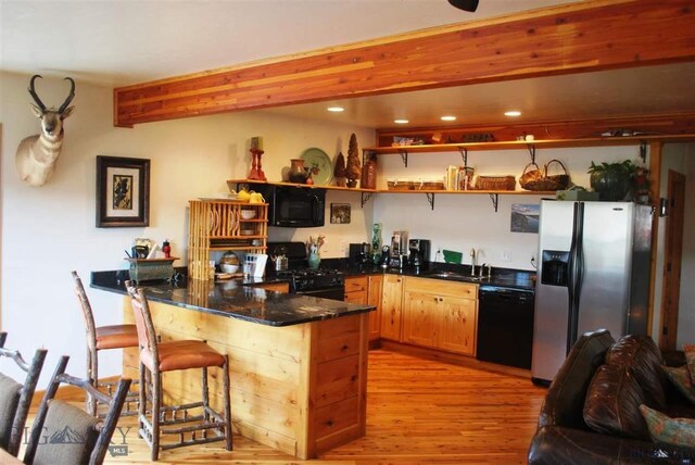 kitchen with black appliances, sink, beam ceiling, light hardwood / wood-style floors, and kitchen peninsula