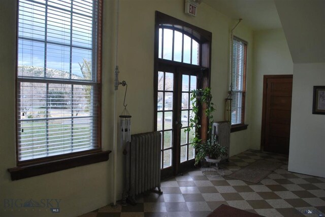 entryway with french doors, dark tile patterned flooring, and radiator heating unit