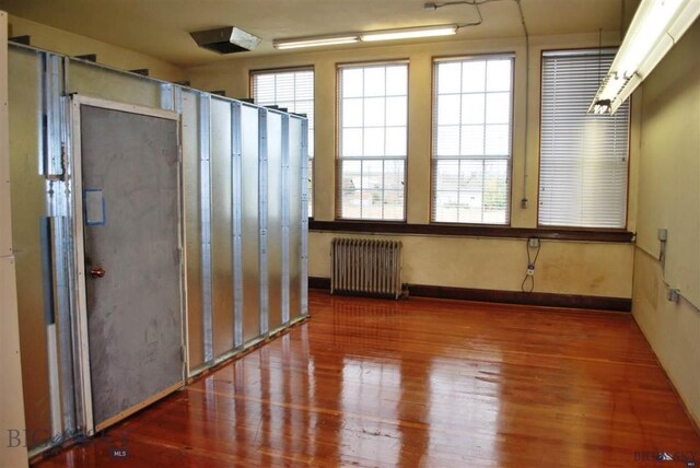 empty room with dark hardwood / wood-style floors and radiator heating unit