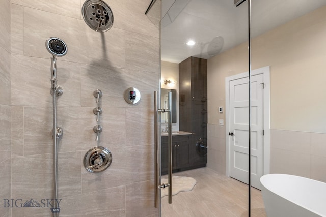 bathroom with vanity, independent shower and bath, and tile walls