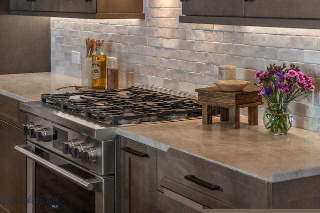 kitchen with high end stove, light stone counters, and tasteful backsplash