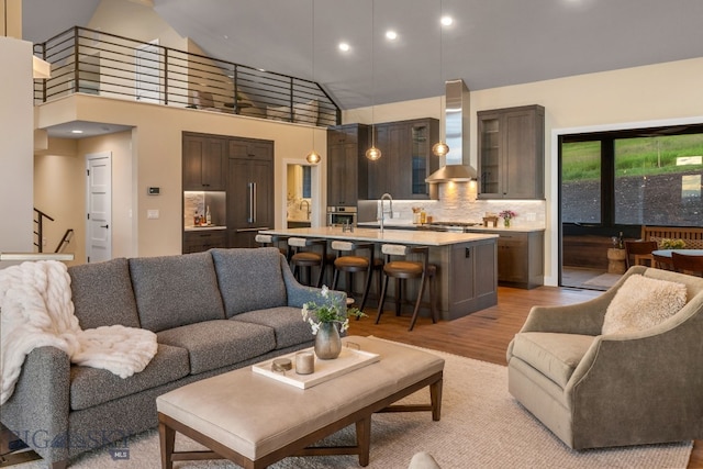 living room featuring sink, high vaulted ceiling, and light wood-type flooring