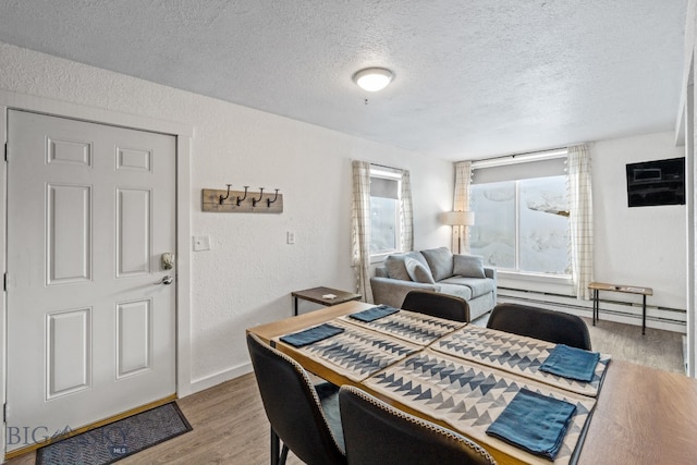 dining space featuring a baseboard heating unit, a textured ceiling, and hardwood / wood-style flooring