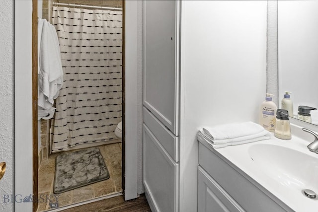 bathroom with hardwood / wood-style floors, toilet, walk in shower, and vanity