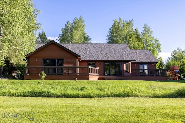 back of property featuring a lawn, a deck, and a shingled roof