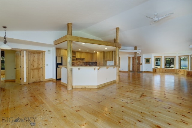 kitchen featuring hanging light fixtures, lofted ceiling, kitchen peninsula, and light hardwood / wood-style flooring