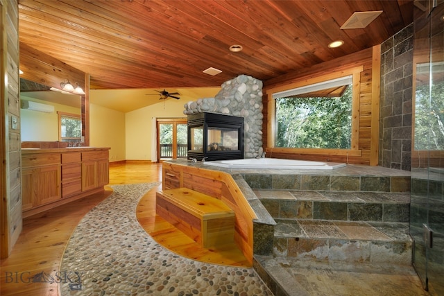 bedroom featuring a stone fireplace, an AC wall unit, lofted ceiling, wood ceiling, and light wood-type flooring