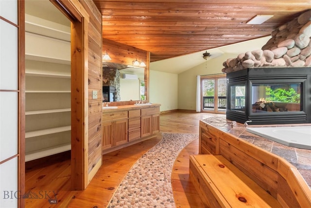 3127 Augusta Dr, Bozeman, MT 59715 - full bathroom featuring a multi sided fireplace, vanity, vaulted ceiling, wood finished floors, and a garden tub
