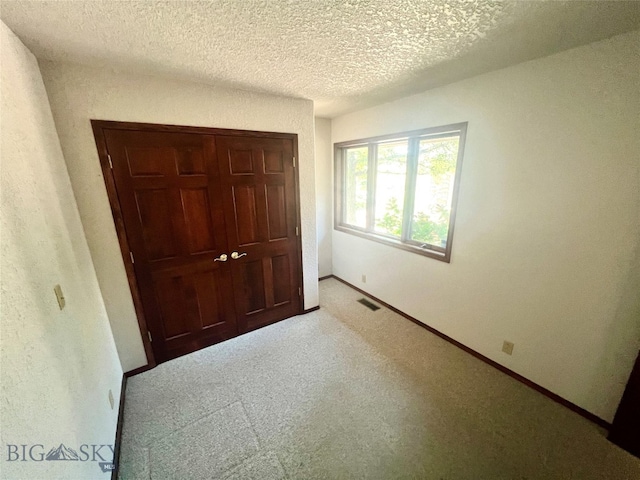 unfurnished bedroom with a closet, carpet flooring, and a textured ceiling