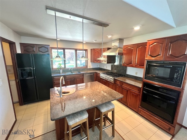 kitchen with black appliances, wall chimney range hood, sink, a breakfast bar, and a kitchen island with sink