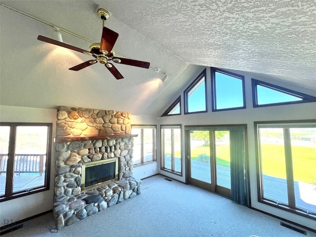 living room with ceiling fan, carpet, a textured ceiling, a stone fireplace, and lofted ceiling