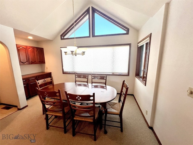 carpeted dining area with lofted ceiling and a chandelier