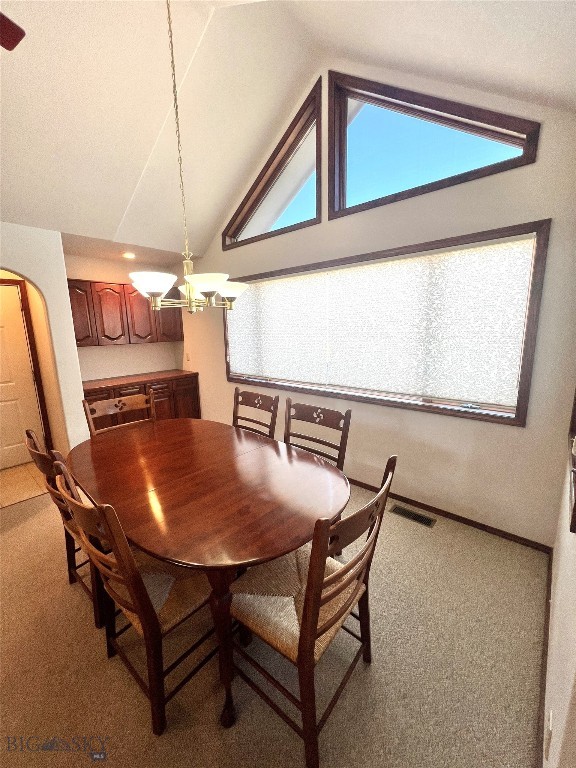 dining area with carpet floors and high vaulted ceiling