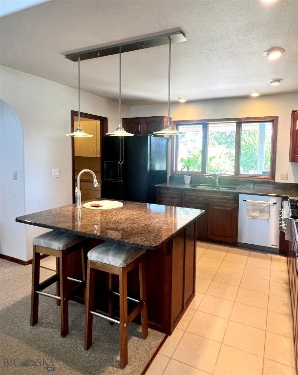 kitchen featuring black fridge with ice dispenser, sink, dishwashing machine, and pendant lighting