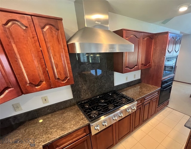 kitchen featuring dark stone counters, tasteful backsplash, ventilation hood, stainless steel gas cooktop, and light tile patterned floors