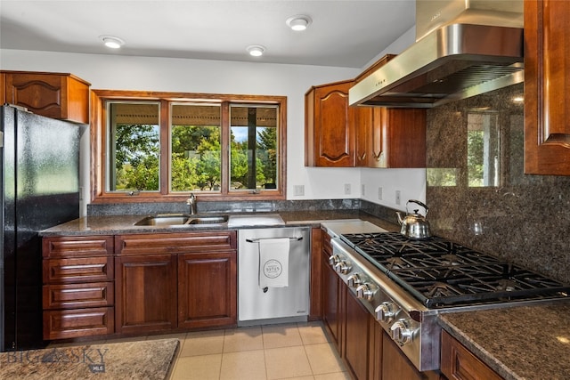 kitchen featuring sink, black fridge, a wealth of natural light, and wall chimney range hood