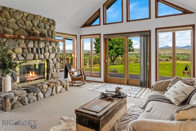 sunroom featuring a stone fireplace, lofted ceiling, a mountain view, and plenty of natural light