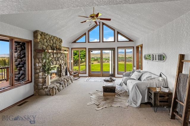 interior space featuring a stone fireplace, vaulted ceiling, and ceiling fan